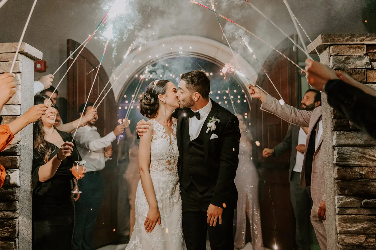 A couple celebrating their wedding outside DOmenico Winery San Carlos entrance with fireworks and streams in the background